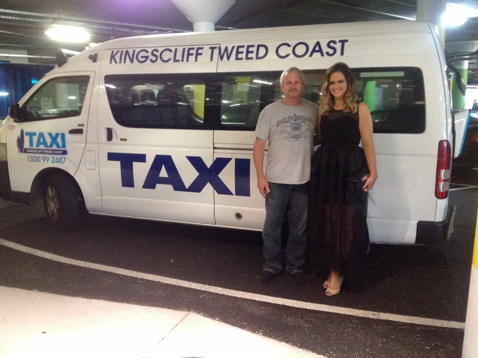 A Man And A Woman Standing In Front Of A Taxi — Kingscliff Tweed Coast Taxis Pty Ltd In Tugun, QLD