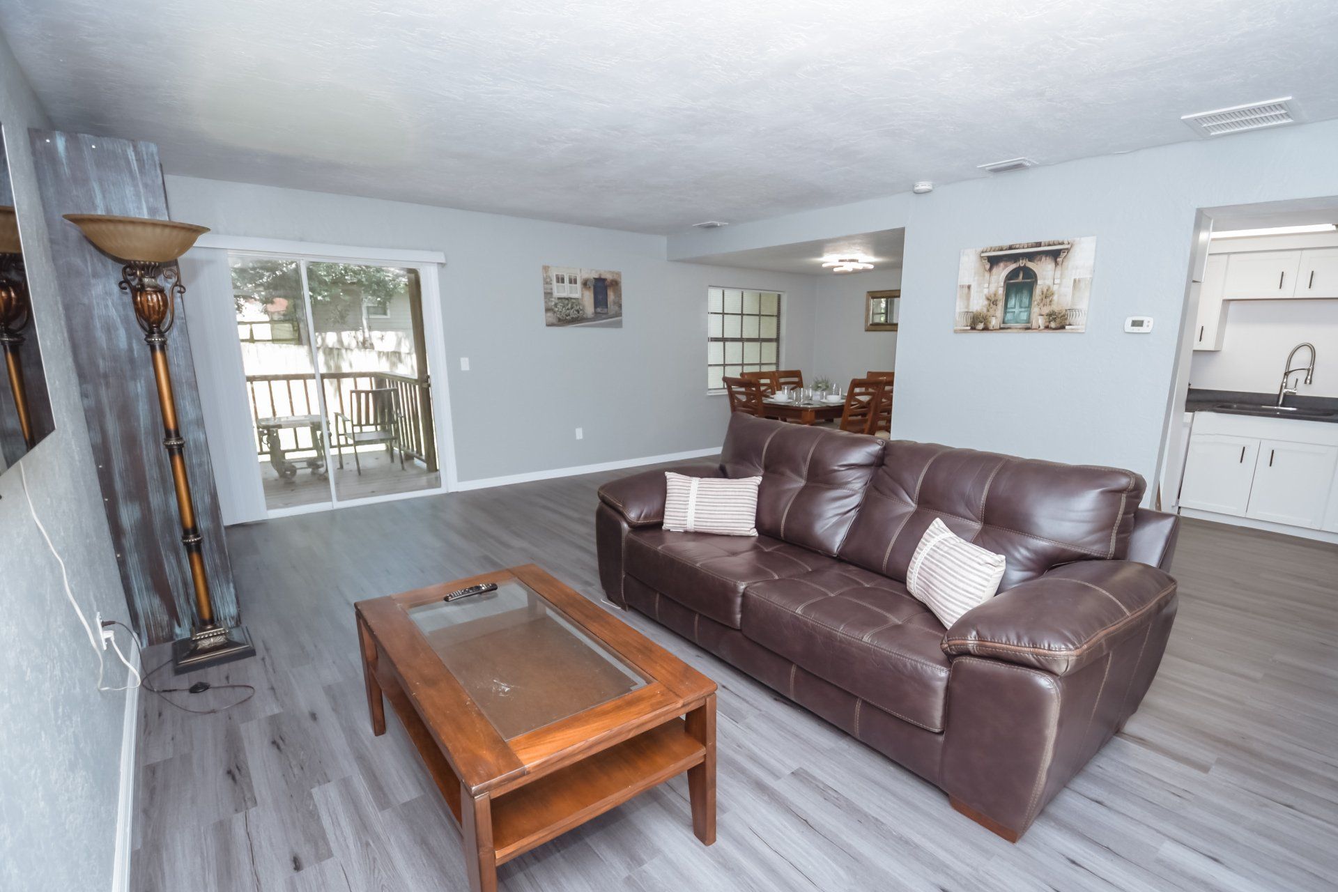 Living room with brown leather sofa, wooden coffee table, and sliding glass door to a balcony.
