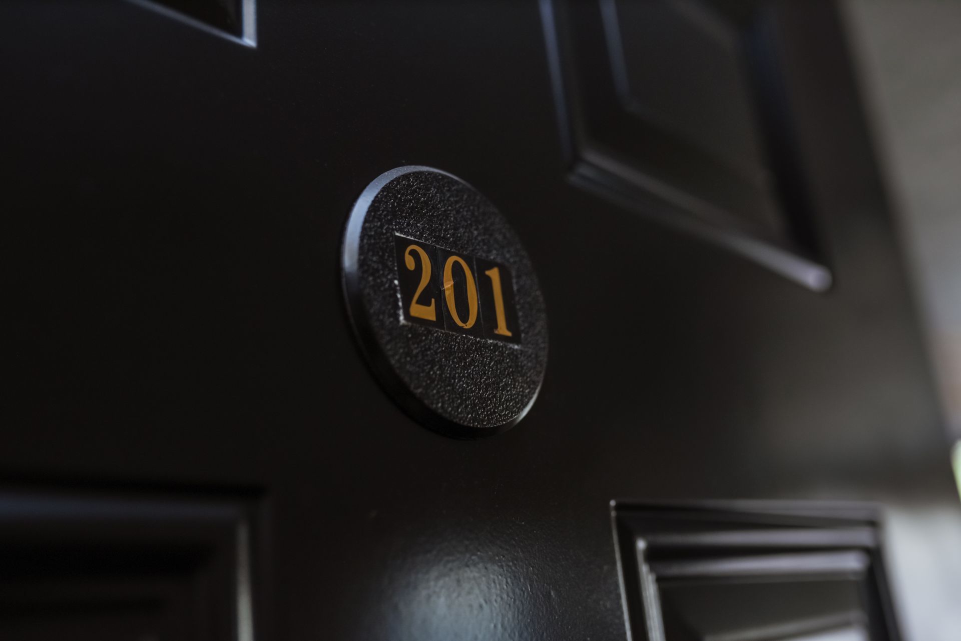 Black door with a circular room number plate that reads 