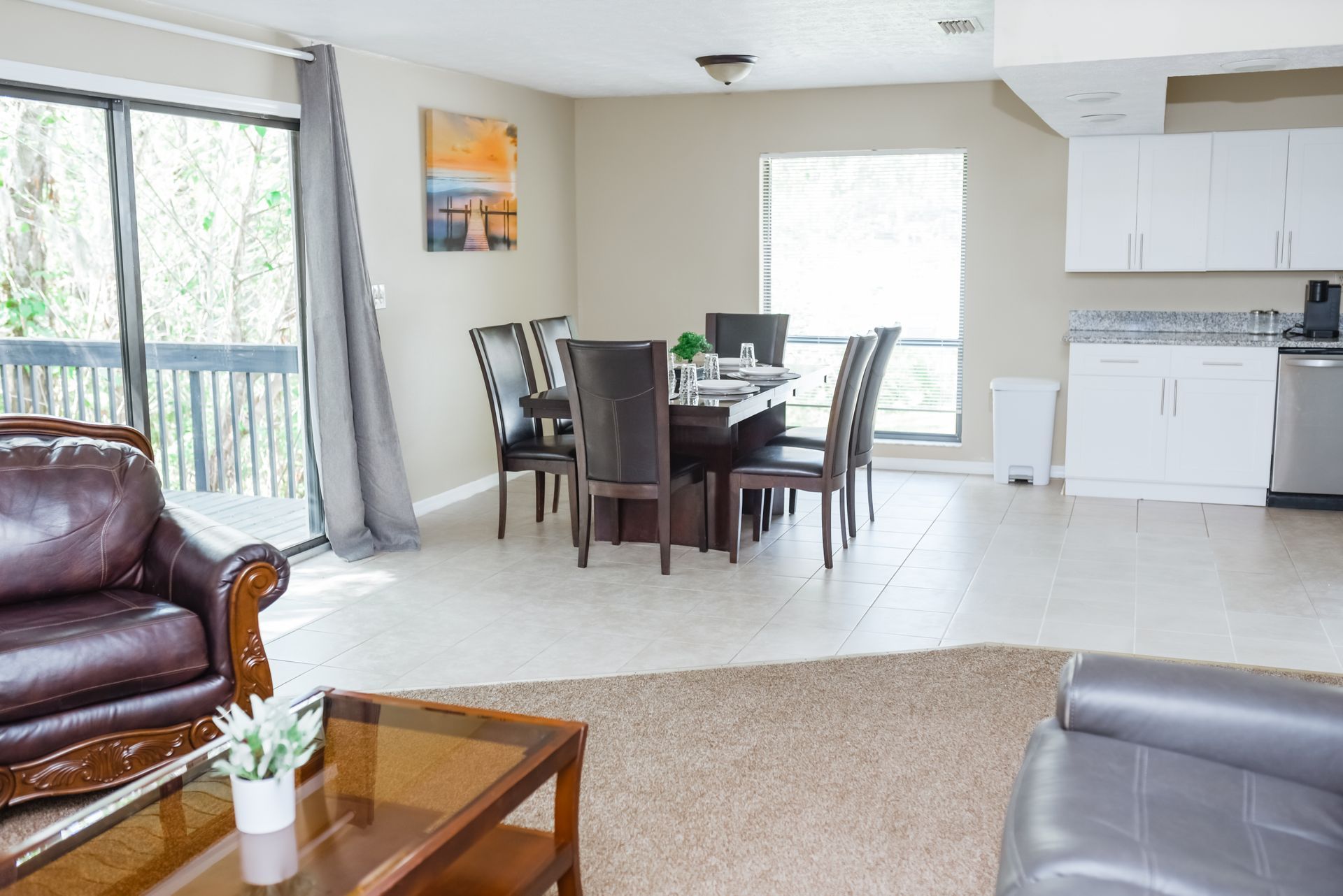 Living room with dining area, brown leather furniture, wooden table, and sliding glass door.