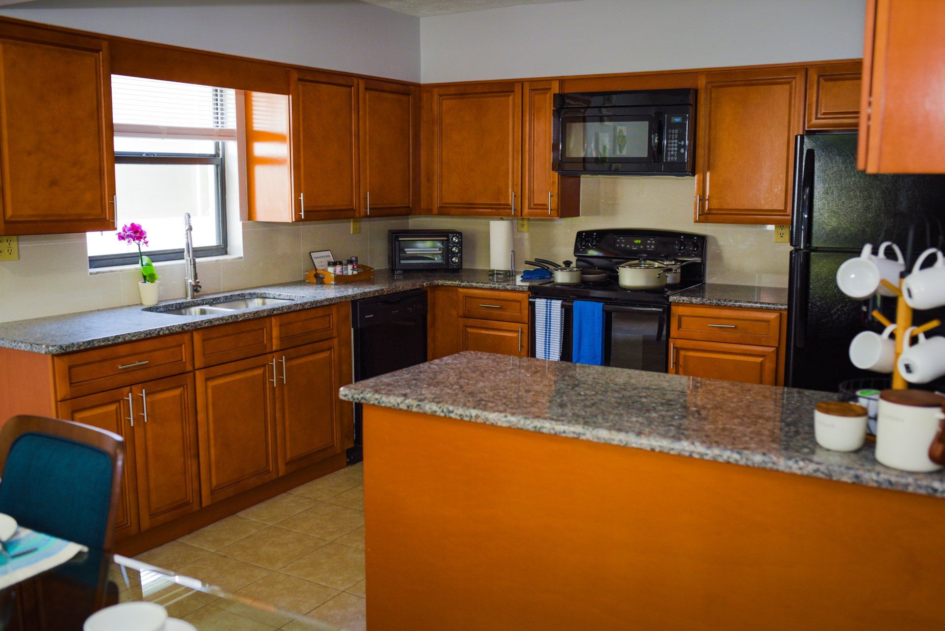 Kitchen with wooden cabinets, black appliances, and granite countertops.