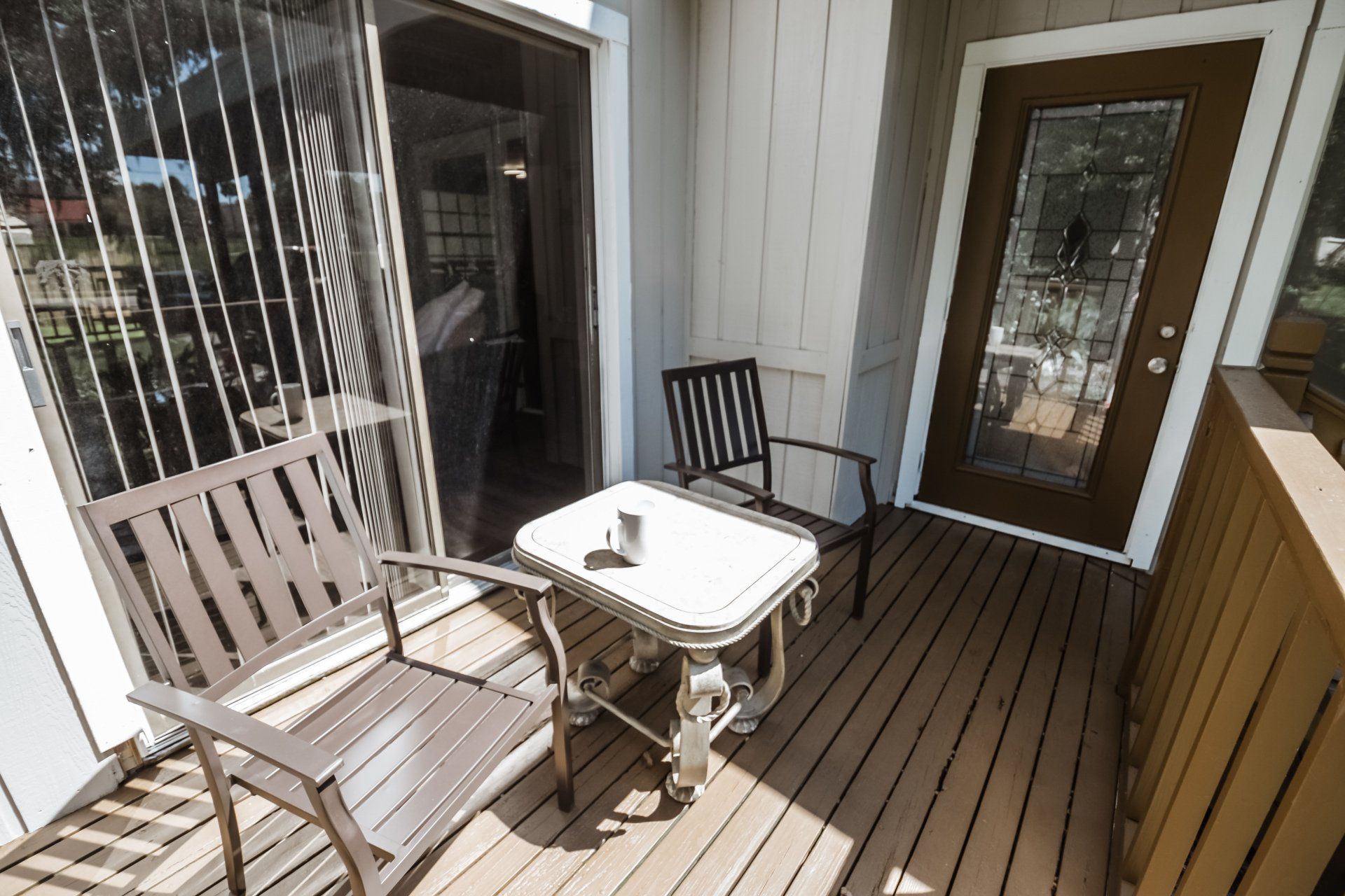 Small balcony with two chairs, a table, and a glass-paned door.
