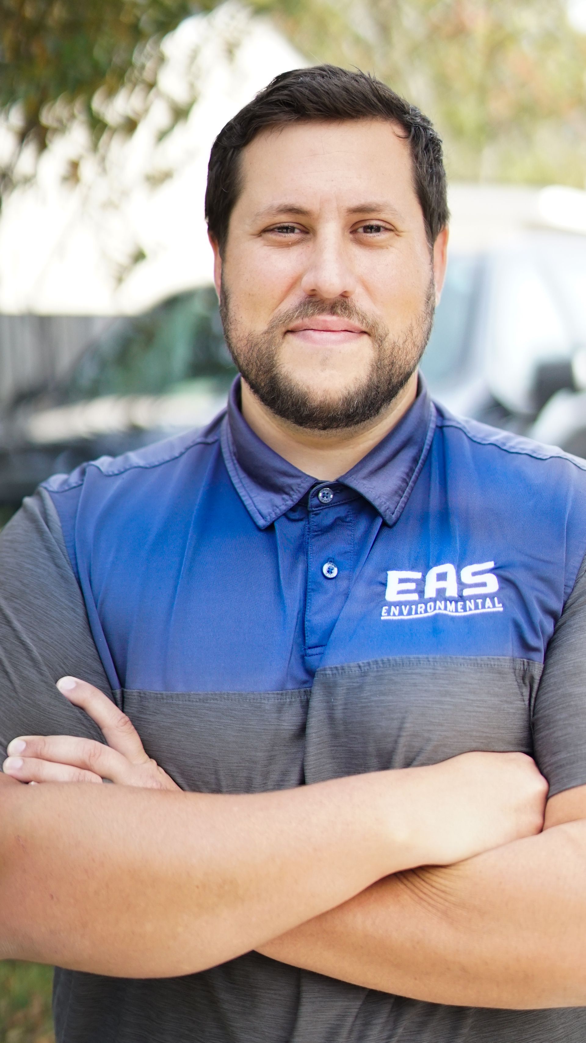Man in blue and gray polo shirt with crossed arms, smiling; EAS Electrical logo visible.