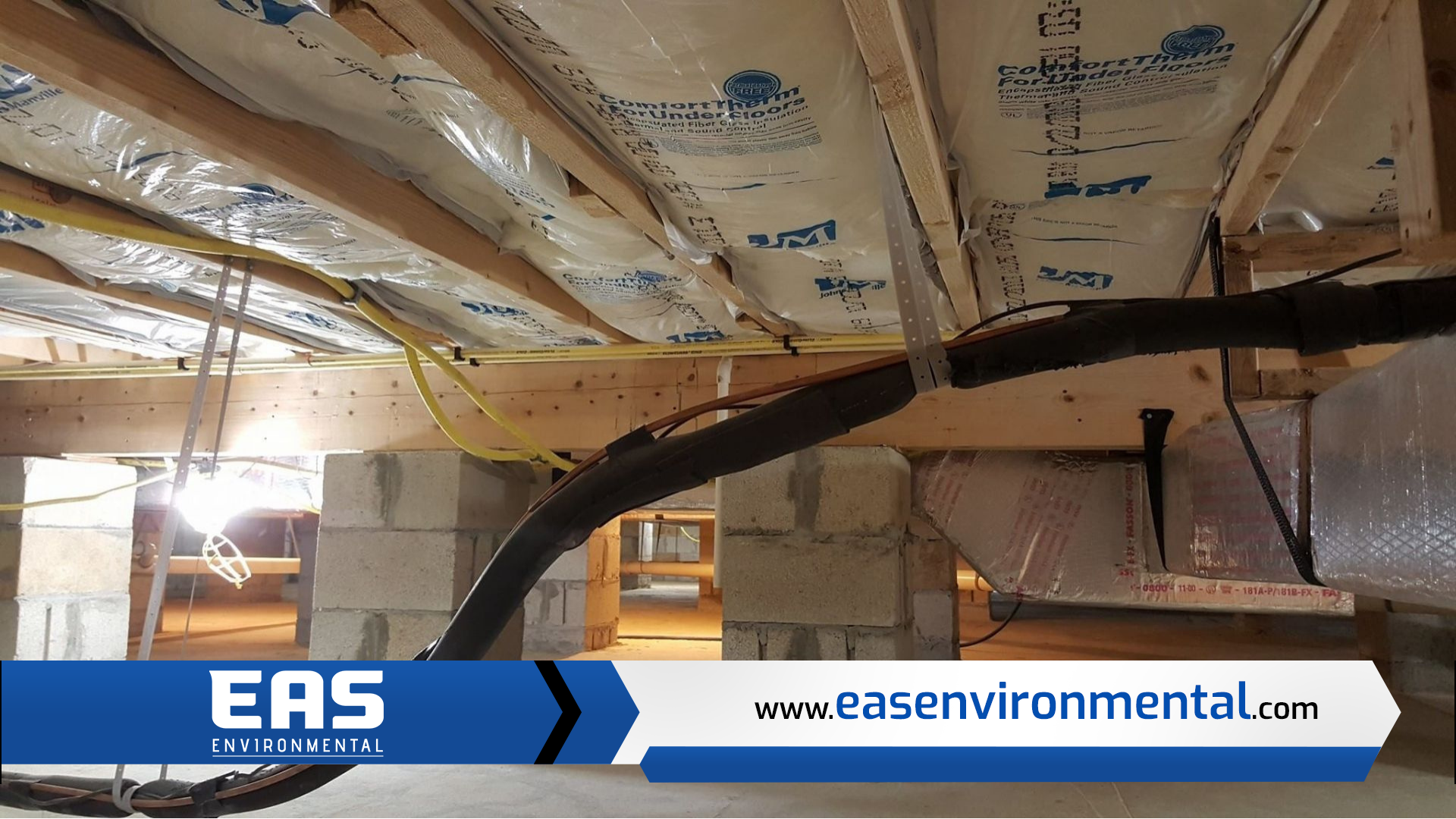 View of crawl space with insulation, cinder block supports, and electrical wiring.