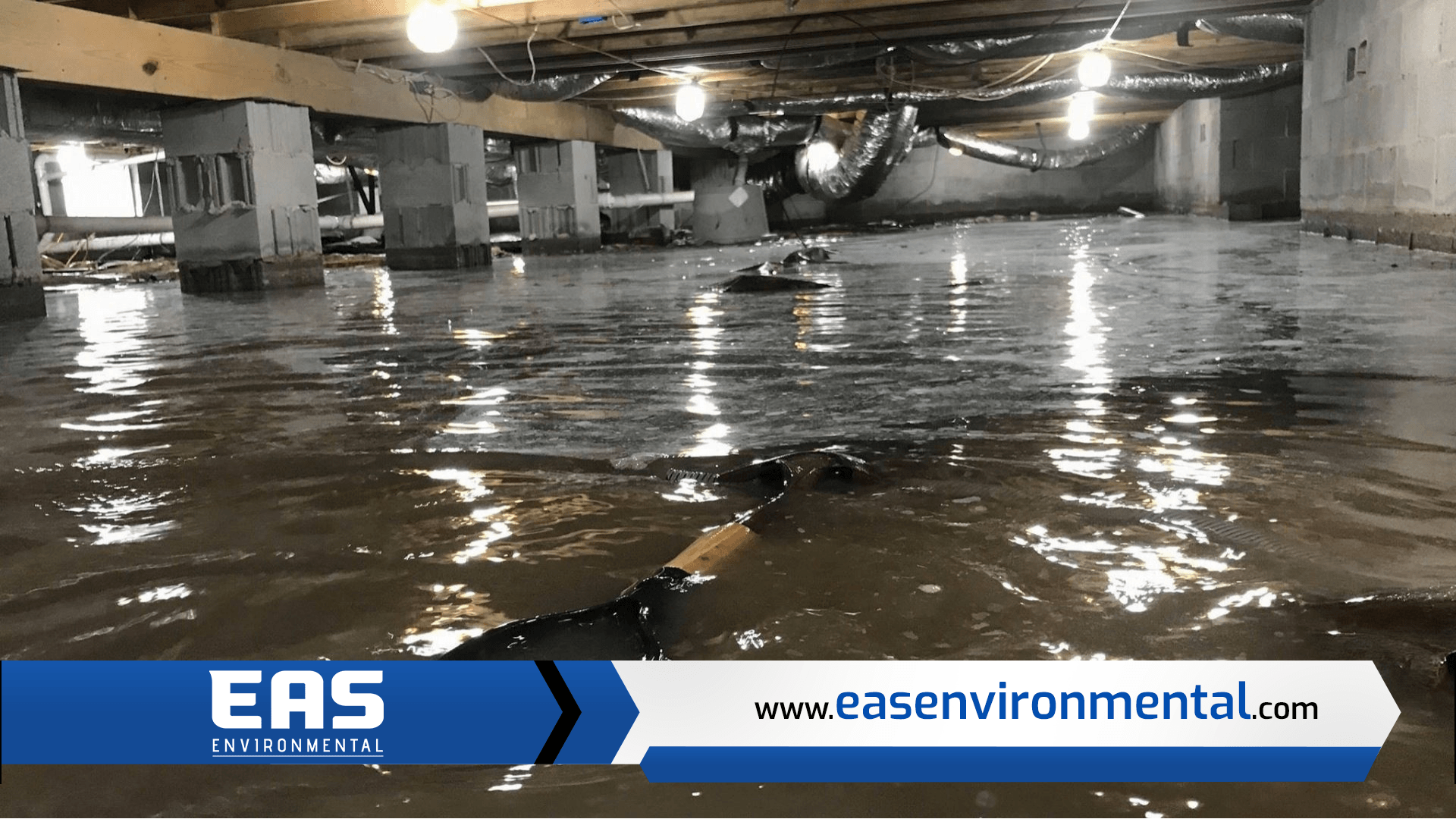 Flooded crawlspace under a structure; water reflects lights and debris.