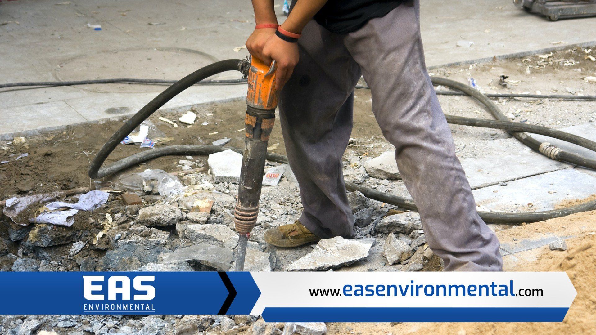 Person using a jackhammer to break up concrete on a construction site.
