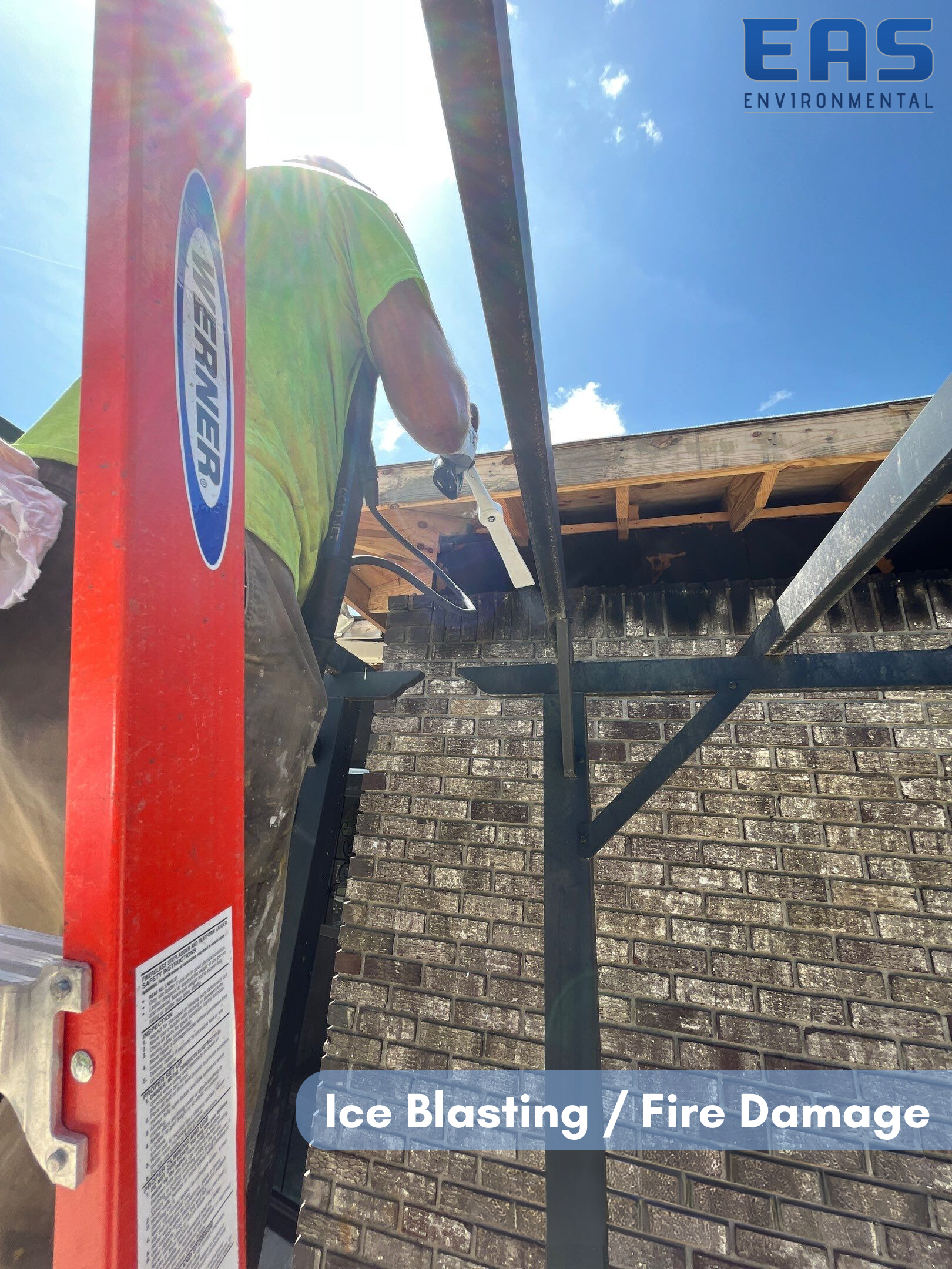 Construction worker ice blasting a roof damaged by fire. Red ladder, blue sky.