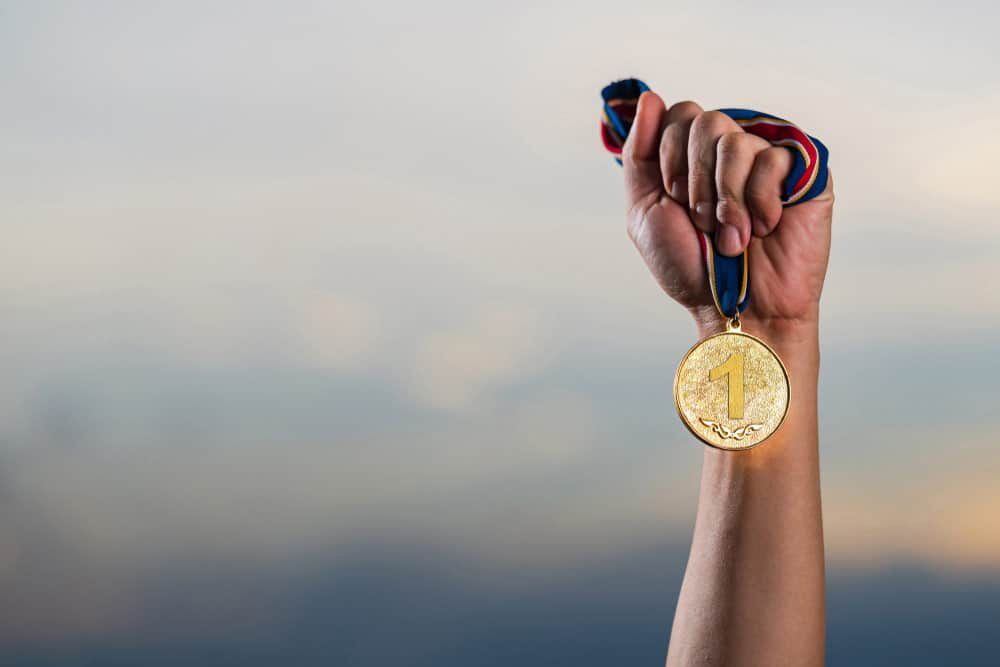 Hand Holding A Gold Sports Medal — NQ Plaques & Trophies In Kirwan, QLD