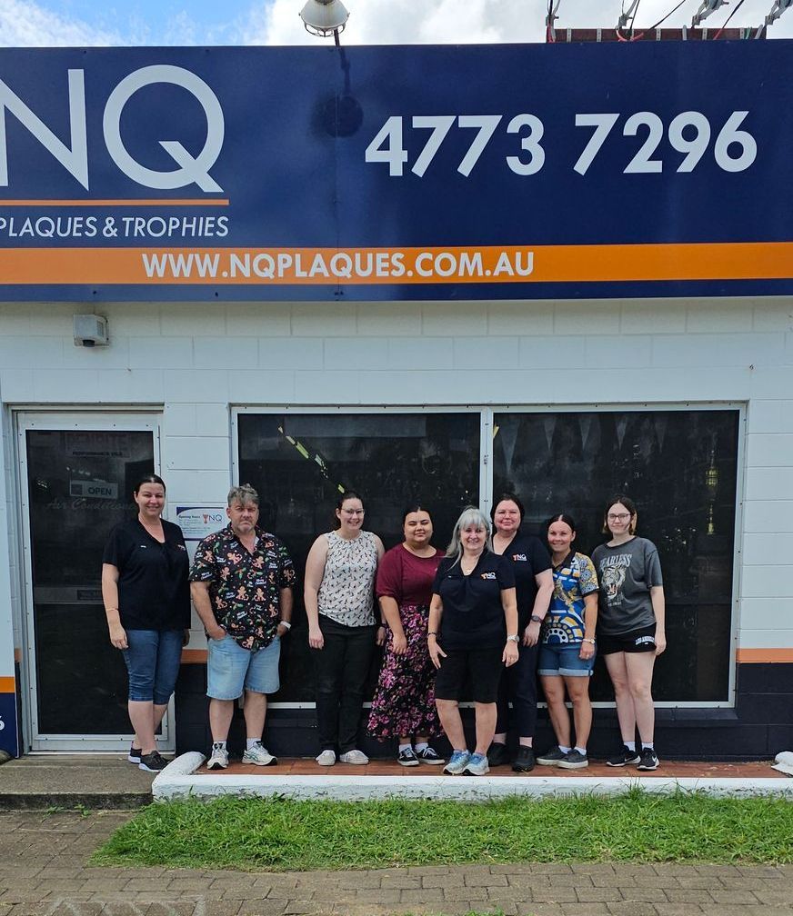 Group of people posing in front of a storefront that reads 