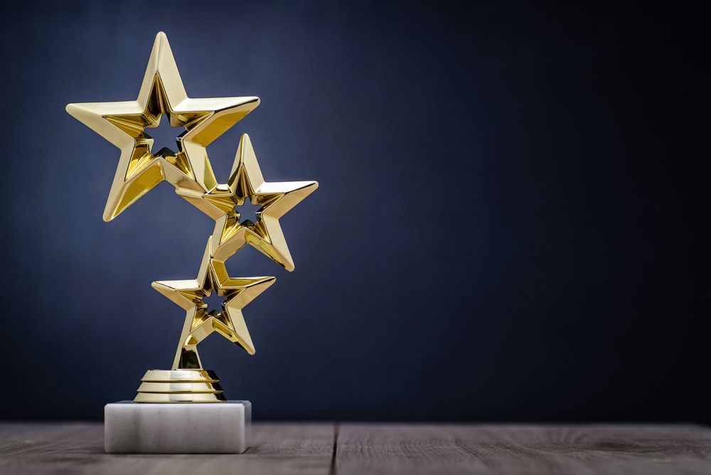 A Trophy With Three Gold Stars On A Wooden Table — NQ Plaques & Trophies In Mount Isa, QLD