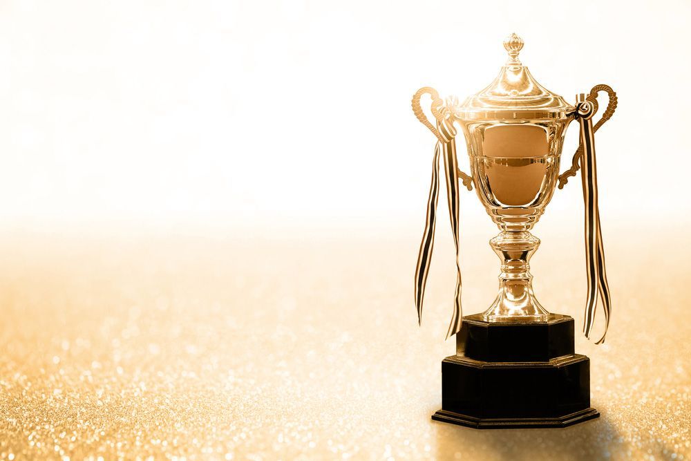 A Gold Trophy Is Sitting On A Table With A White Background — NQ Plaques & Trophies In Cairns, QLD