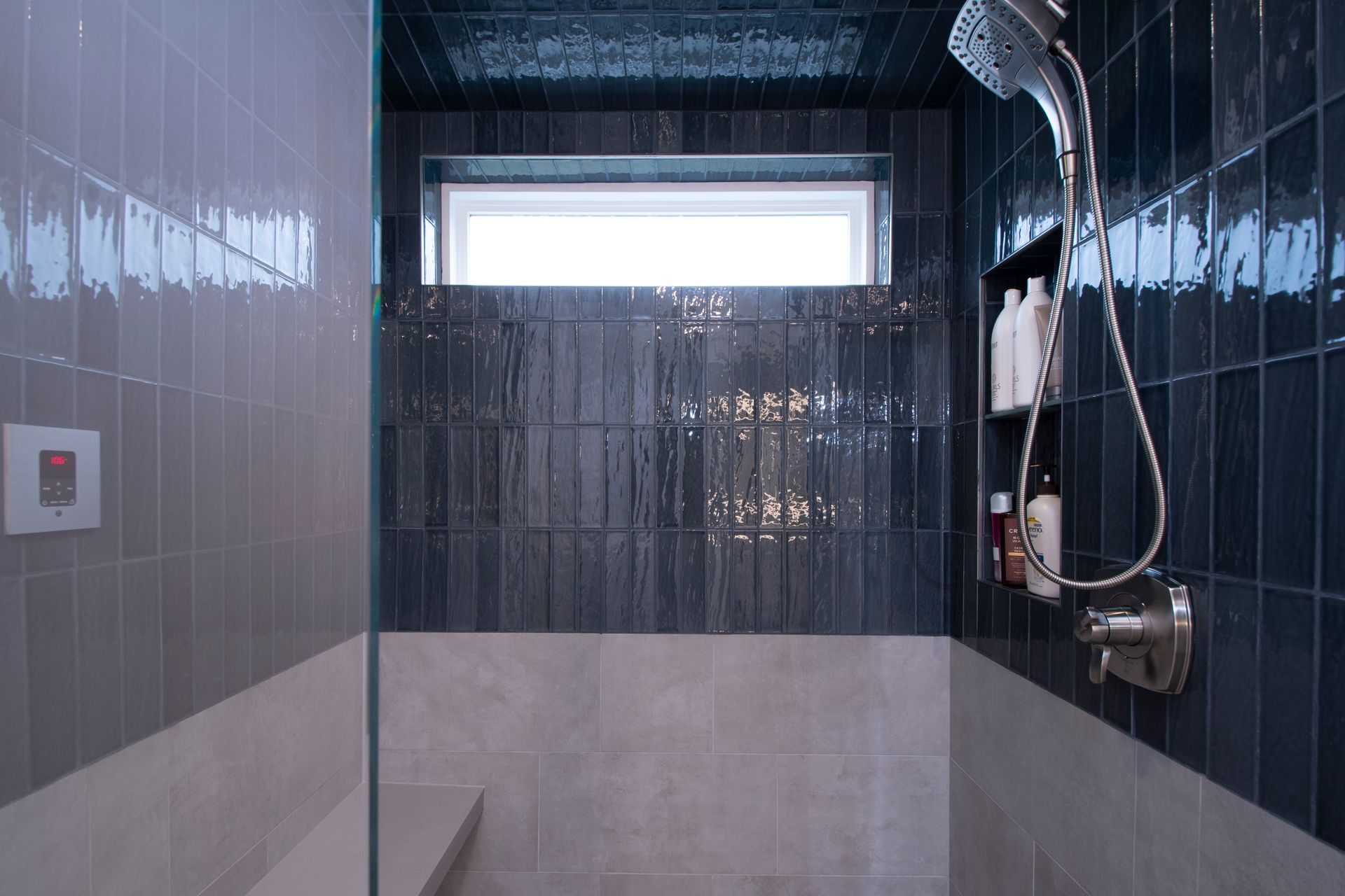 A blue-tiled shower stall with a frosted window and wall-mounted shower fixtures.