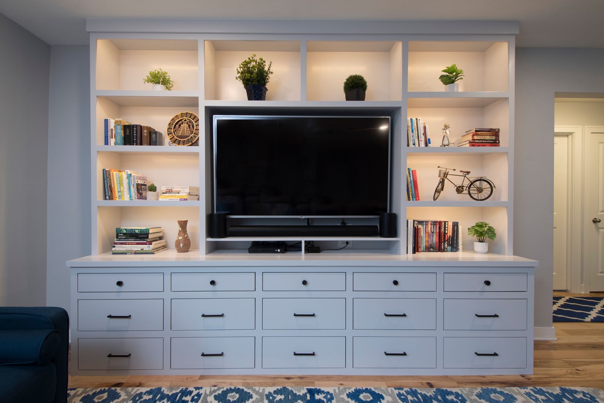 Built-in living room TV wall with shelves, decor, and a white console cabinet