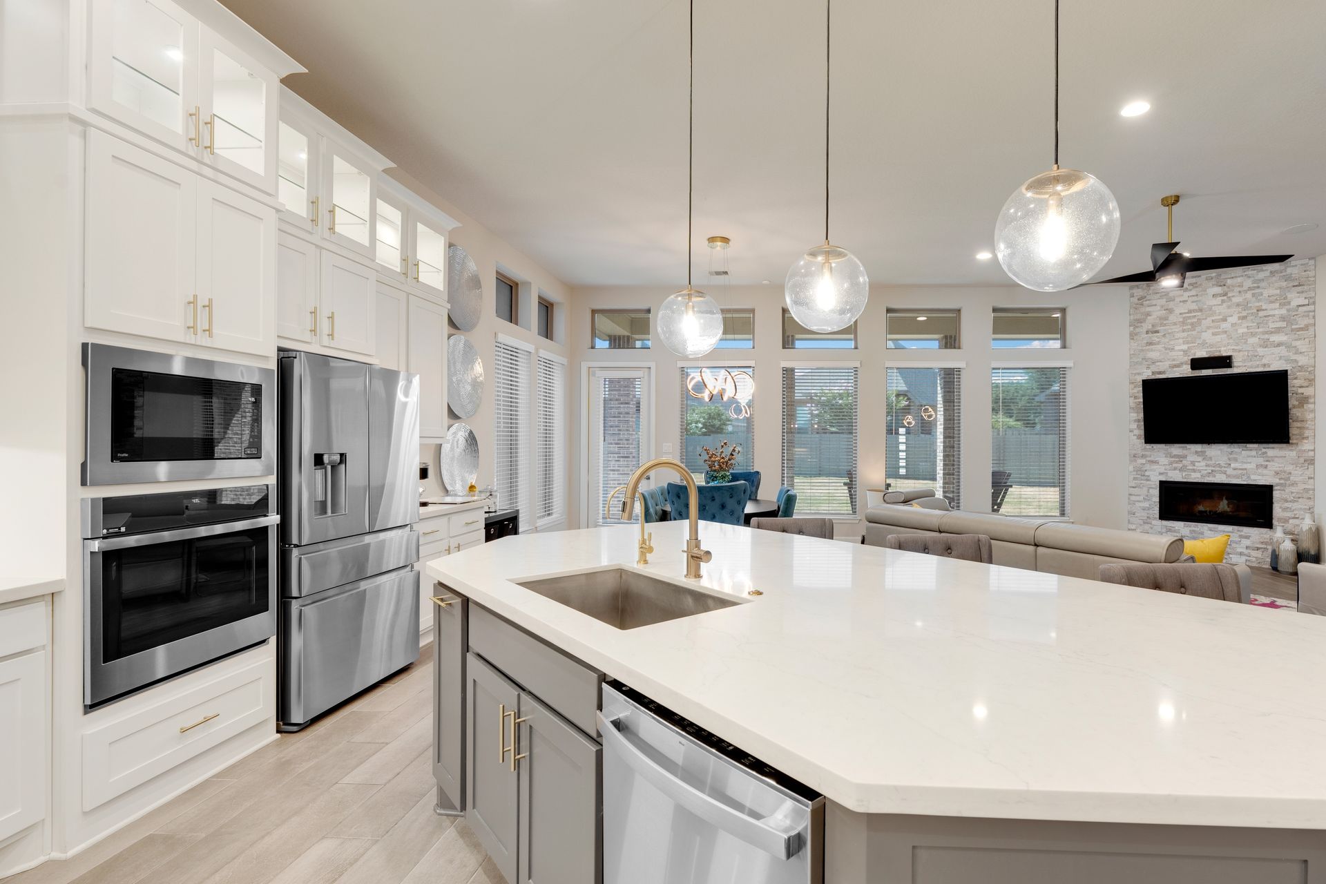 Bright modern white kitchen with island, stainless appliances, and pendant lights