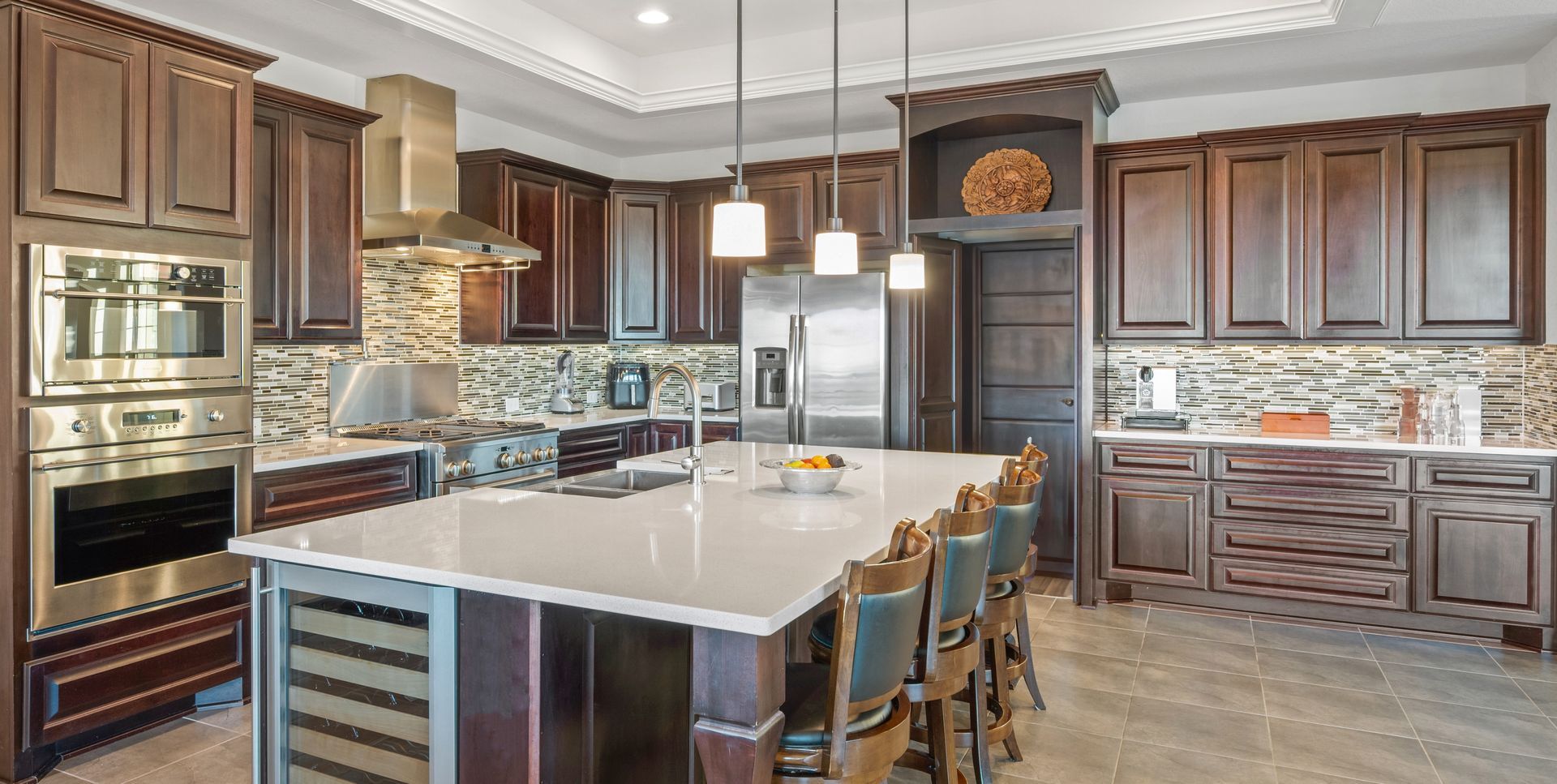 Modern kitchen with dark wood cabinets, marble island, and stainless steel appliances