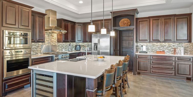 Modern kitchen with dark wood cabinets, stainless appliances, large island, and pendant lights