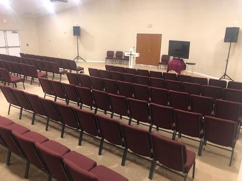 Empty conference room with maroon chairs, a podium, and speakers at the front