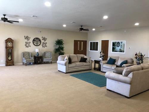 Spacious beige living room with sofas, chairs, wall decor, and recessed ceiling lights