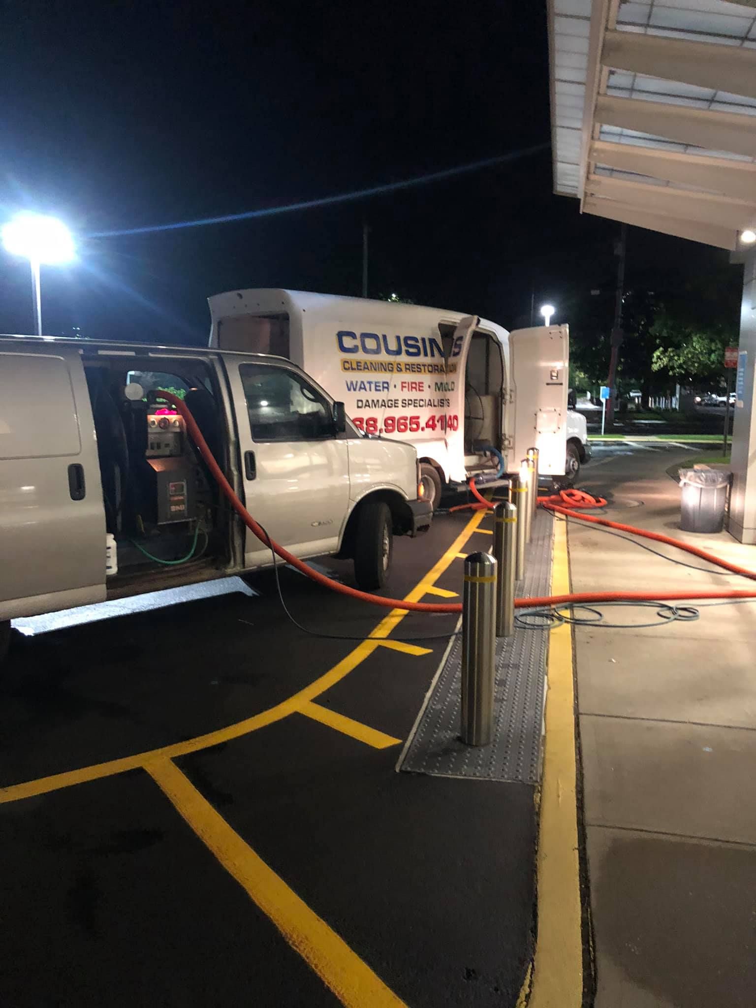 A white van is parked in a parking lot at night.