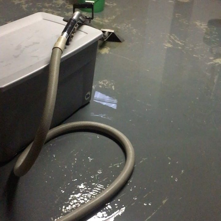A hose is attached to a plastic container on the floor