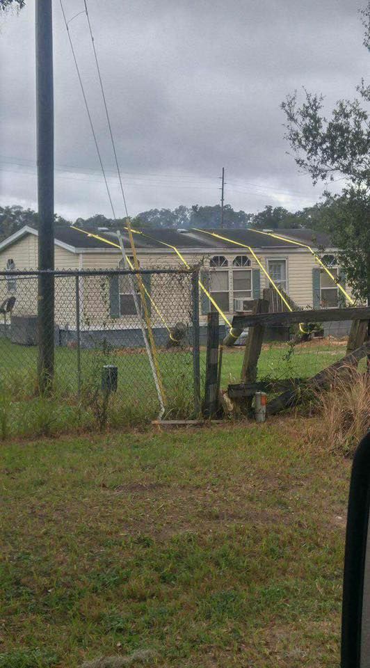 A fence with yellow tape around it in front of a house.