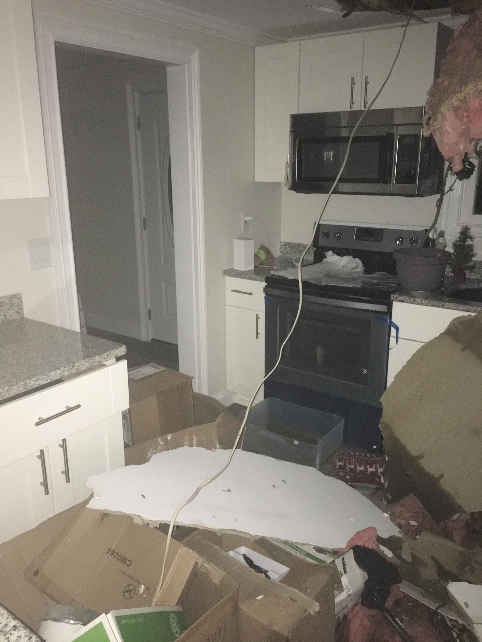 A kitchen with a lot of boxes on the floor and a microwave.