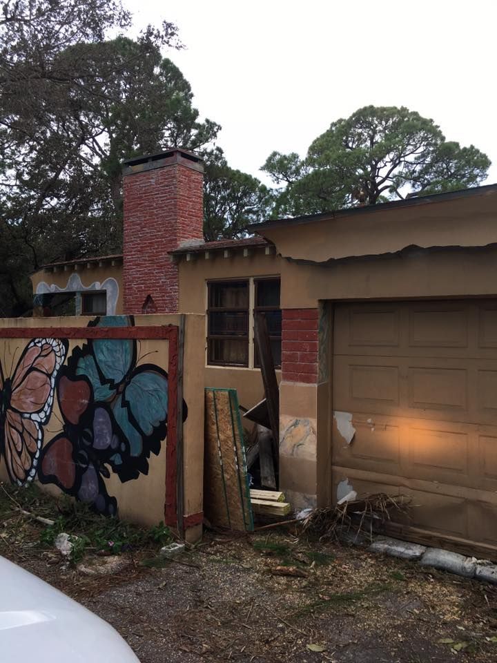 A car is parked in front of a house with graffiti on it