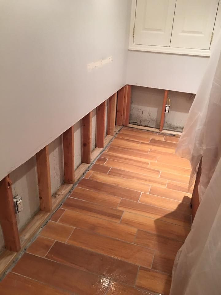 A bathroom with a wooden floor and a white wall.