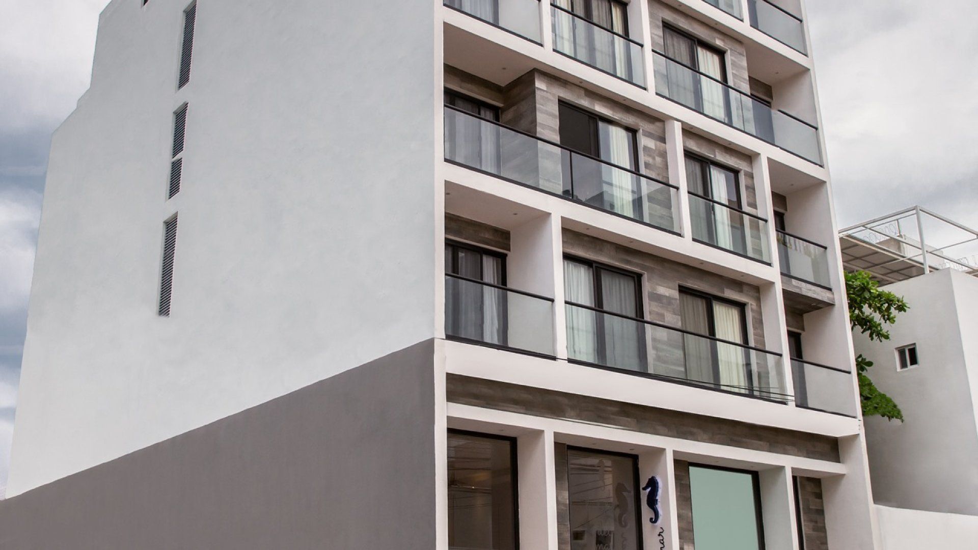 Edificio de apartamentos moderno de color blanco con balcón y grandes ventanales.