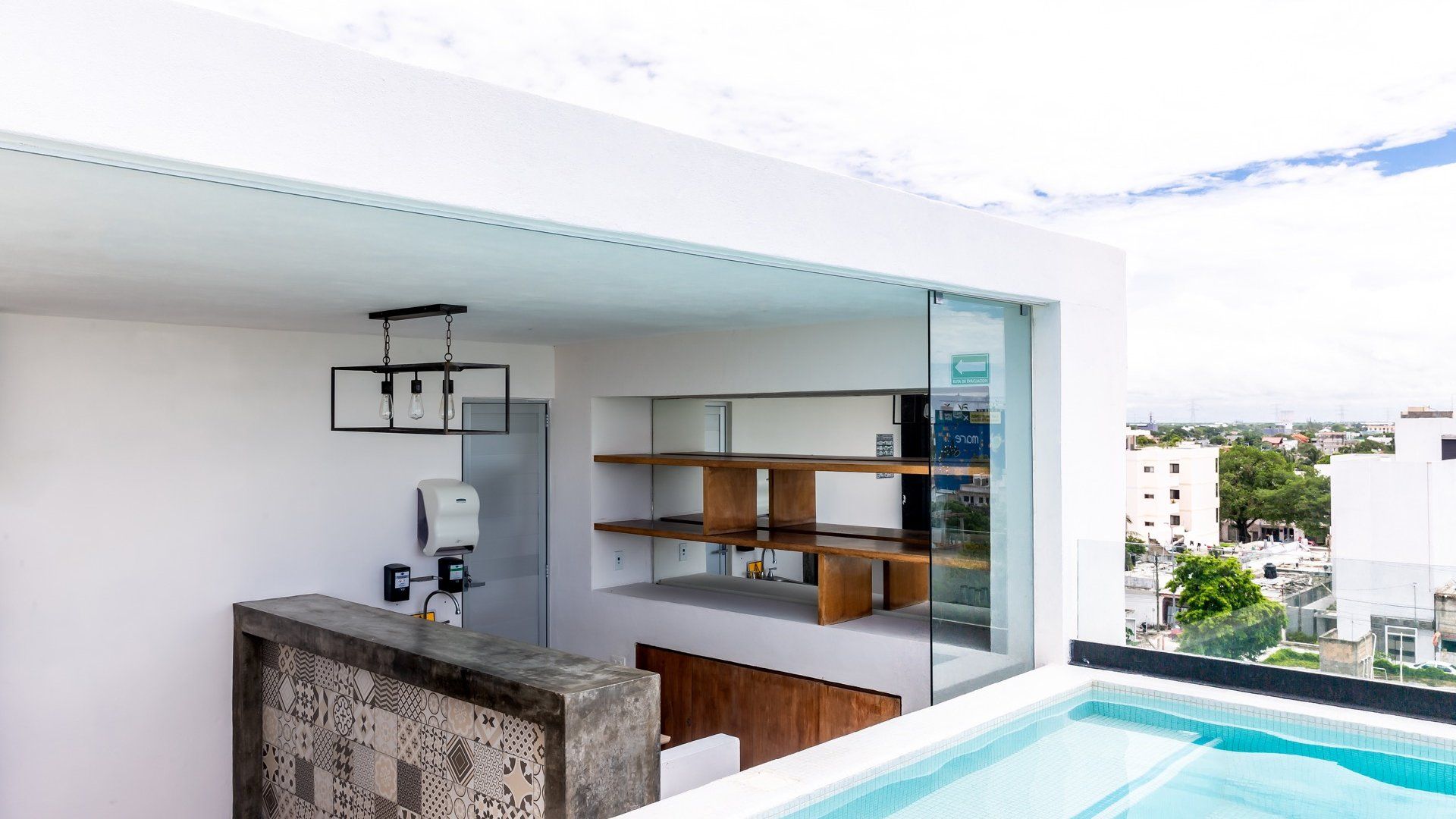 Cocina y bar modernos al aire libre con acceso a una piscina, con estanterías y vistas a la ciudad.