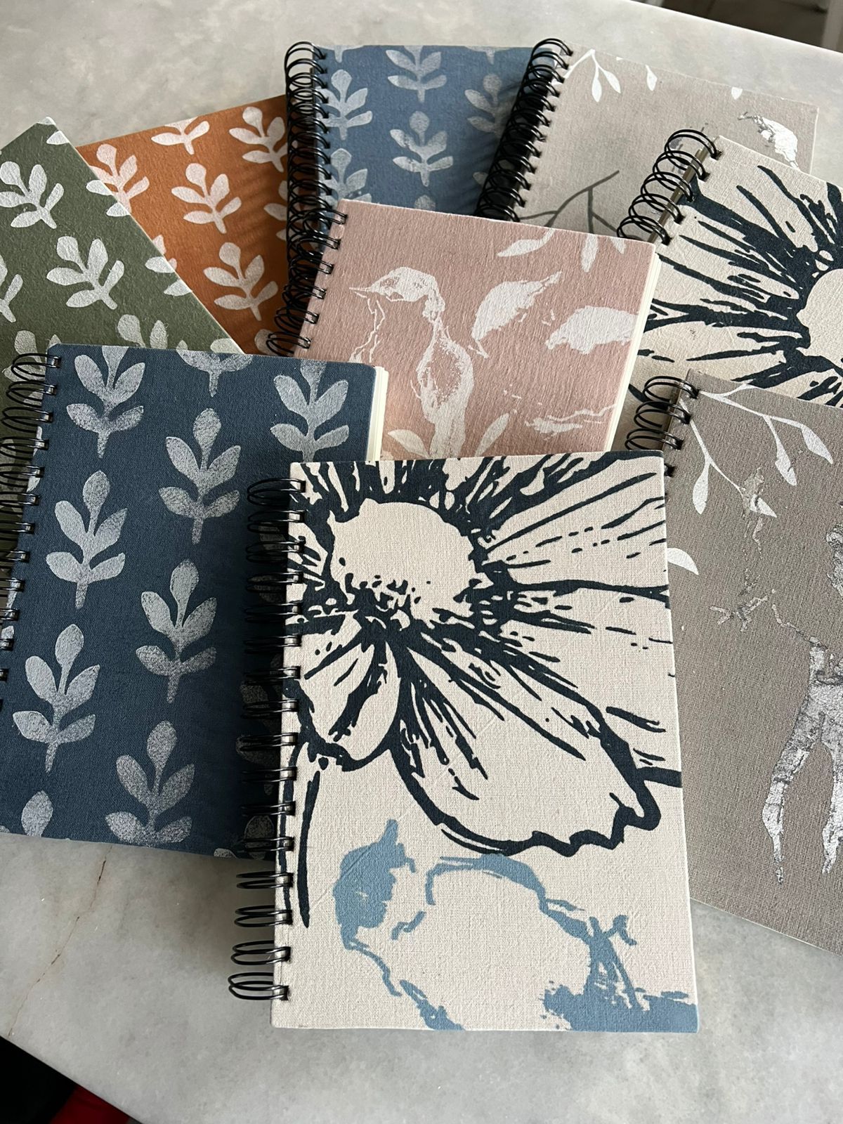 Una selección de cuadernos de espiral con estampado floral, uno abierto en una página con la etiqueta 