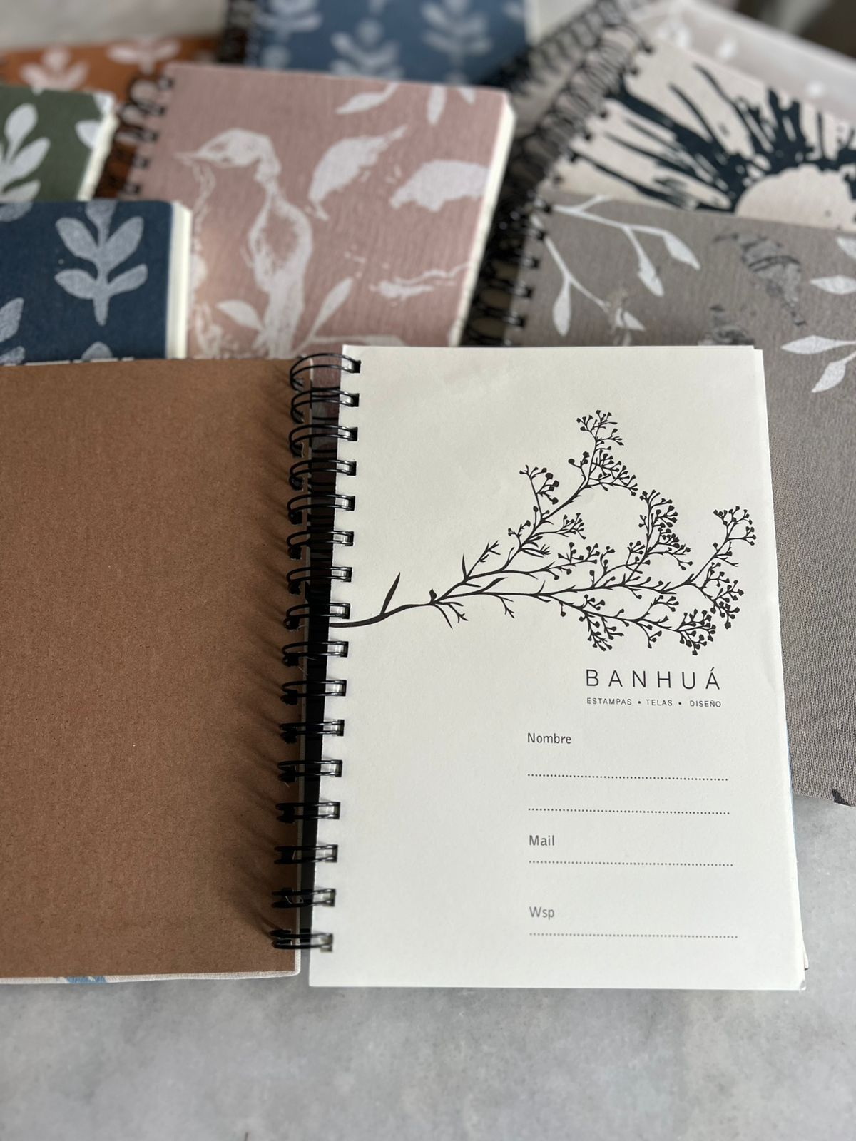 Una selección de cuadernos de espiral con estampado floral, uno abierto en una página con la etiqueta 