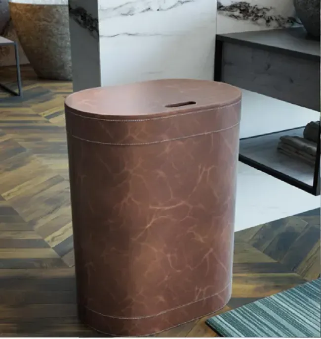 Cesto portabiancheria in pelle marrone con coperchio ovale e fessura, in bagno.