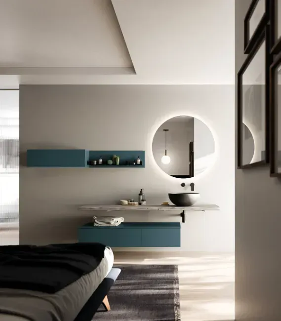 Bagno moderno con mobile lavabo sospeso, mobili color verde acqua, specchio rotondo con luce e letto.
