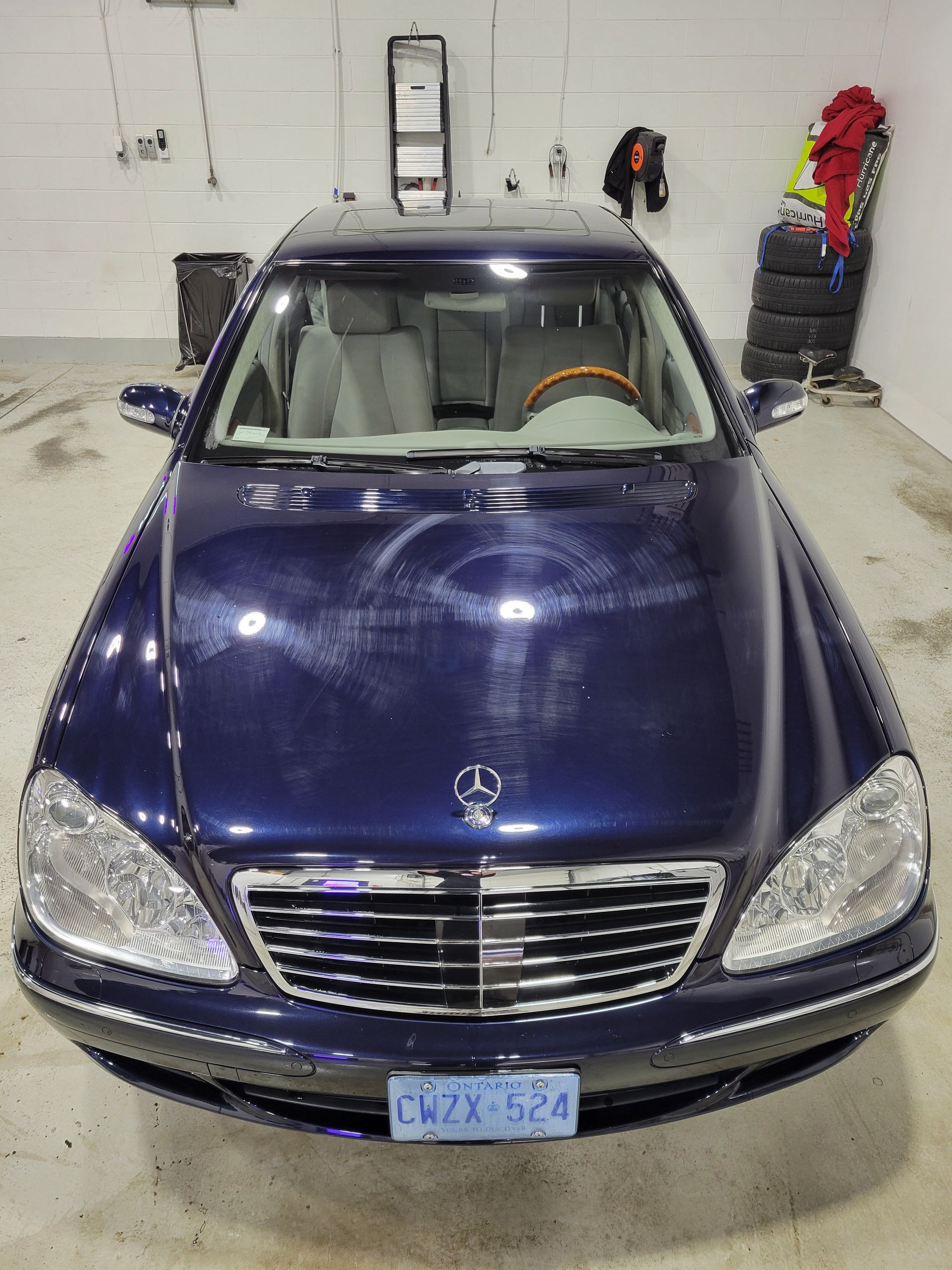 Blue Mercedes sedan parked in a garage, front view.