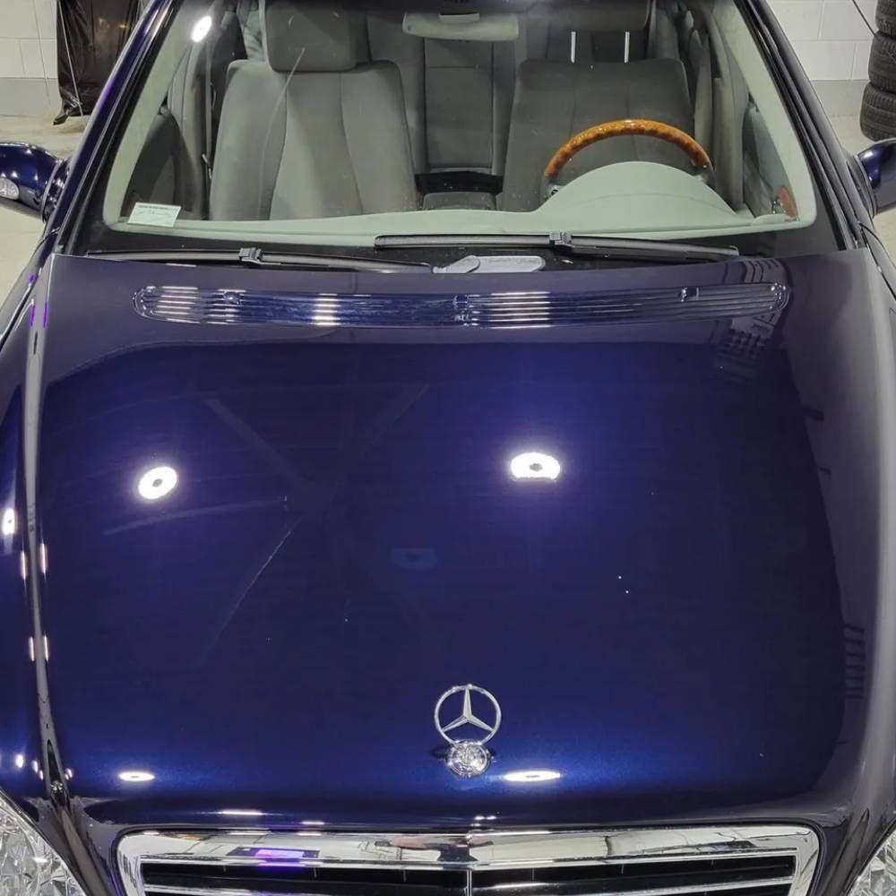 Blue Mercedes-Benz SUV viewed from the front, parked indoors under bright showroom lights