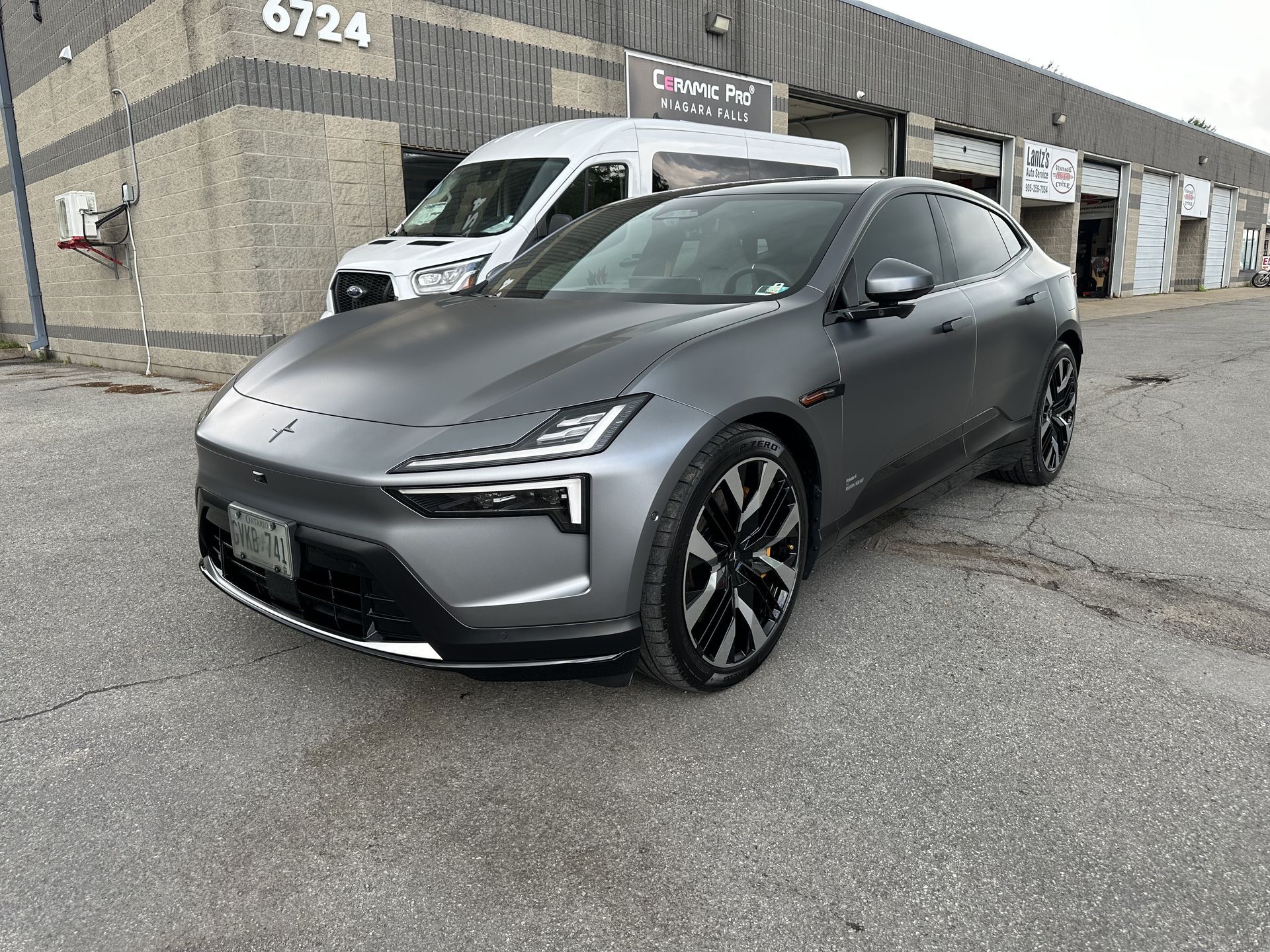 Gray sports SUV parked outside an industrial building, front three-quarter view.