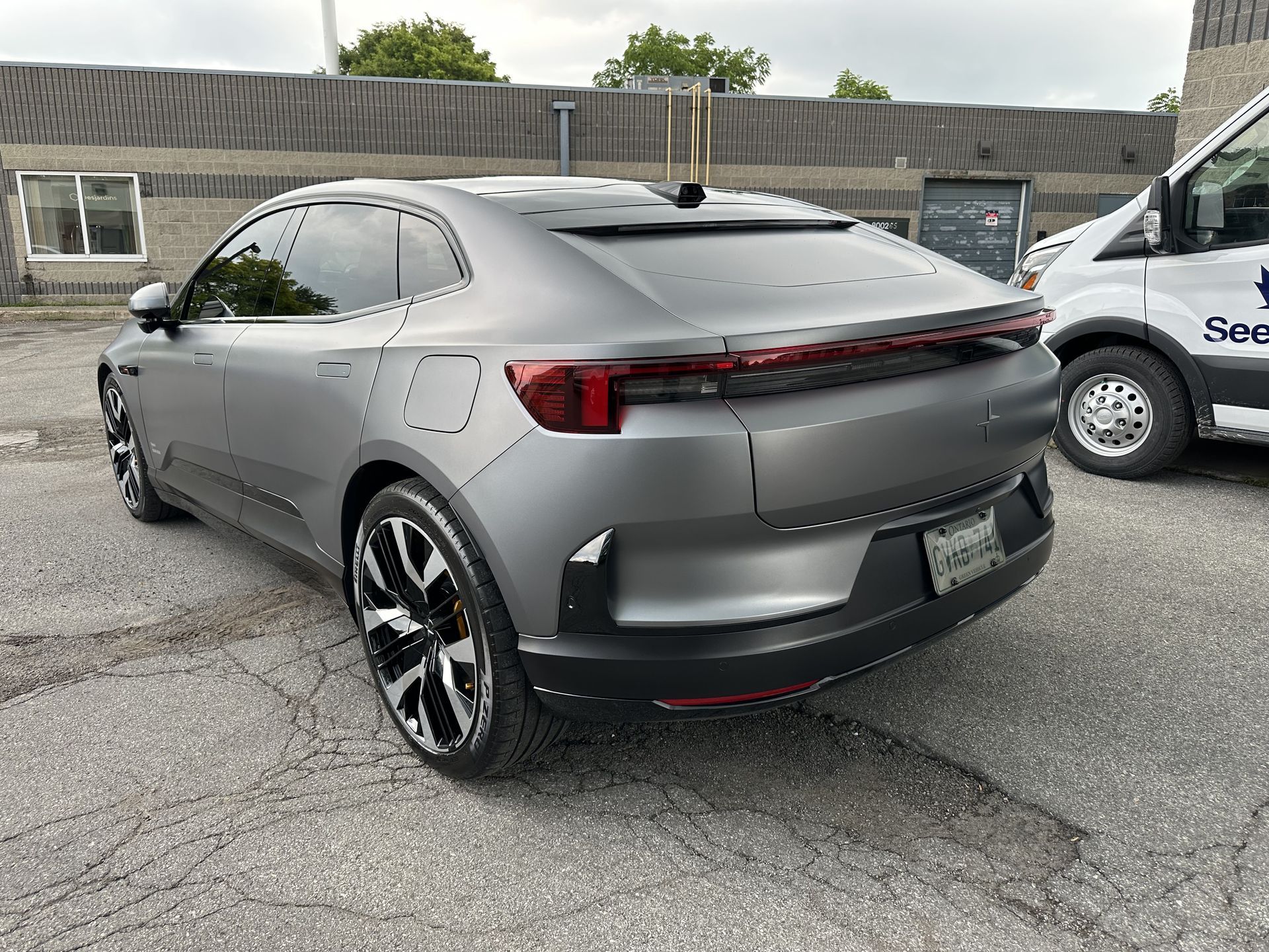 Gray sports sedan parked in a lot, rear three-quarter view with red taillight bar.