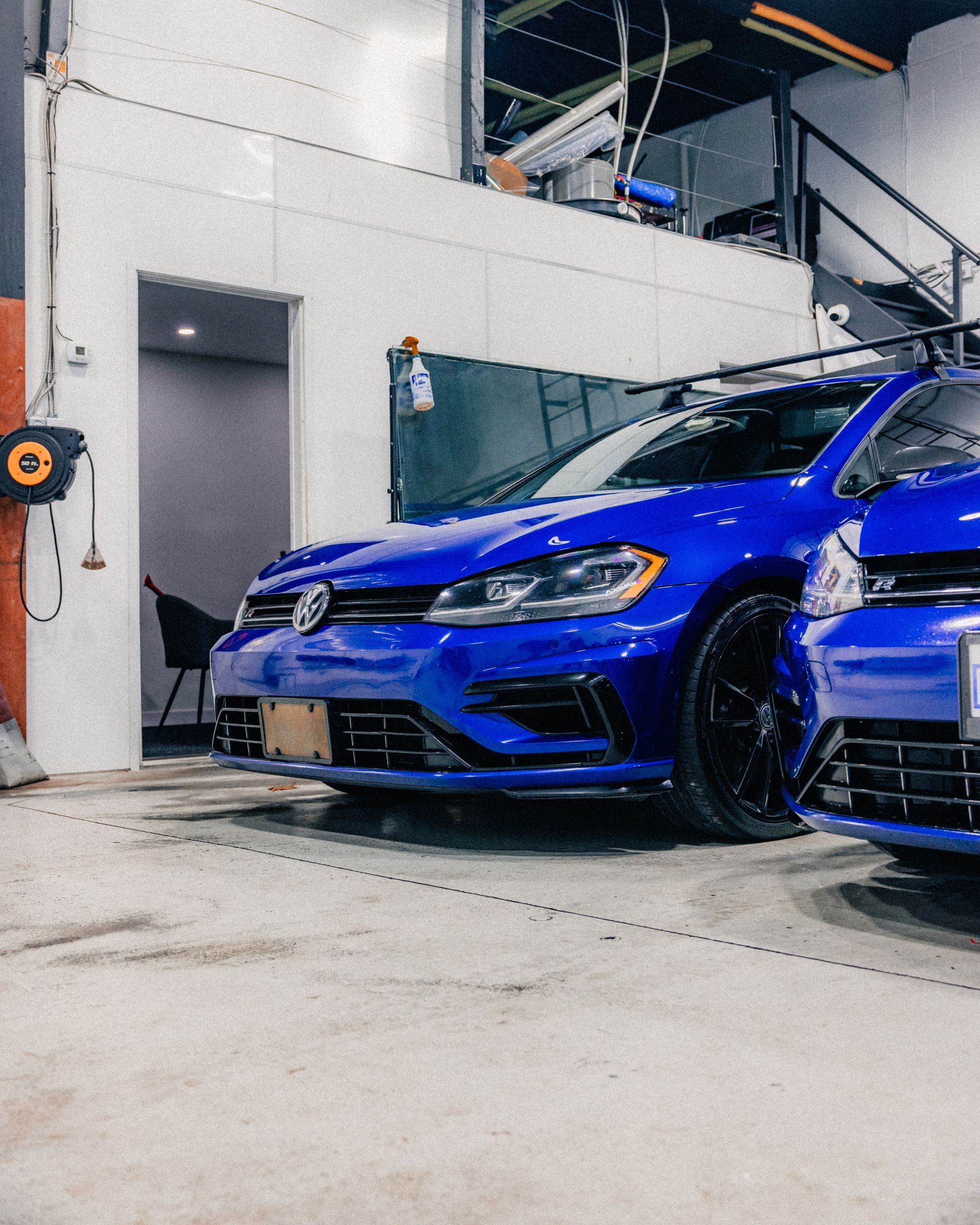 Blue sports car parked in an industrial garage beside another car