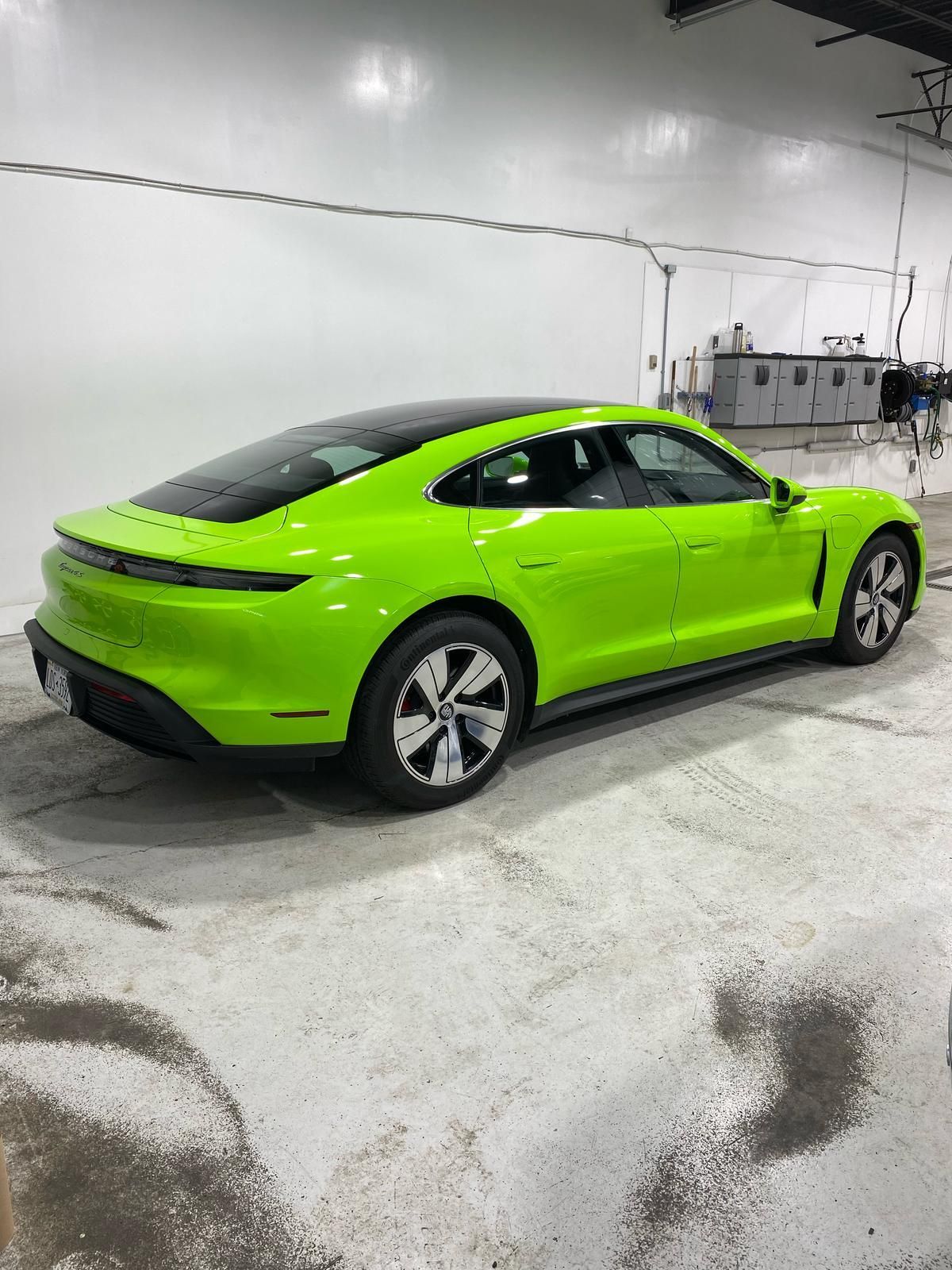 Bright green sports sedan parked indoors on a concrete floor with gray walls