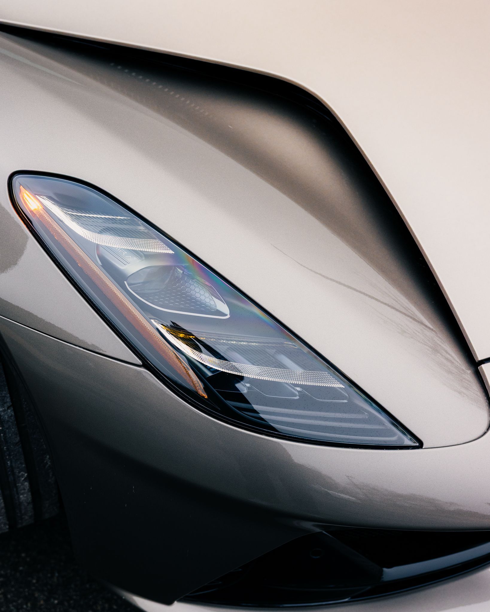 Close-up of a silver sports car headlight and front hood detail