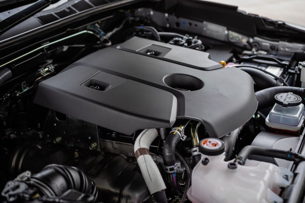 Close-up of a car engine bay with a black engine cover and visible components under the hood