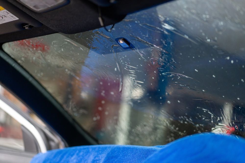 Rain-speckled car windshield with blue cloth on the dashboard and a rearview mirror visible