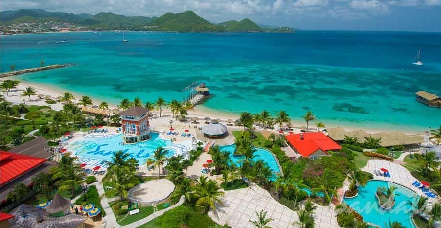 An aerial view of a tropical resort with a large pool and a beach.