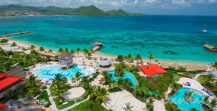 An aerial view of a tropical resort with a large pool and a beach.