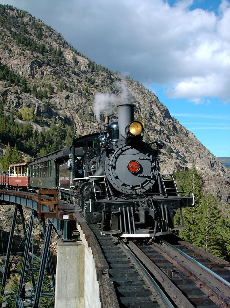 A train going over a bridge with a mountain in the background