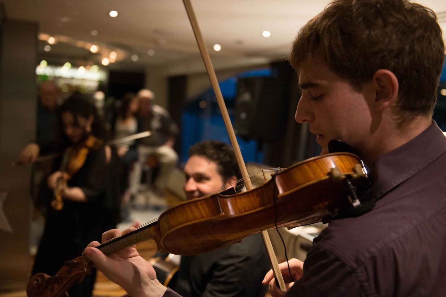 A man is playing a violin in front of a group of people.