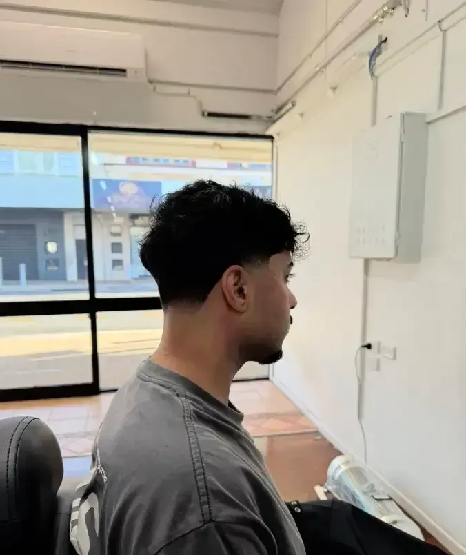 Person in profile sitting in a bright room beside a large window and white wall.