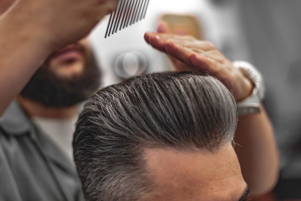 Barber Styling a Man’s Slicked-Back Hair with A Comb — Ultimate Barber in Maryborough, QLD