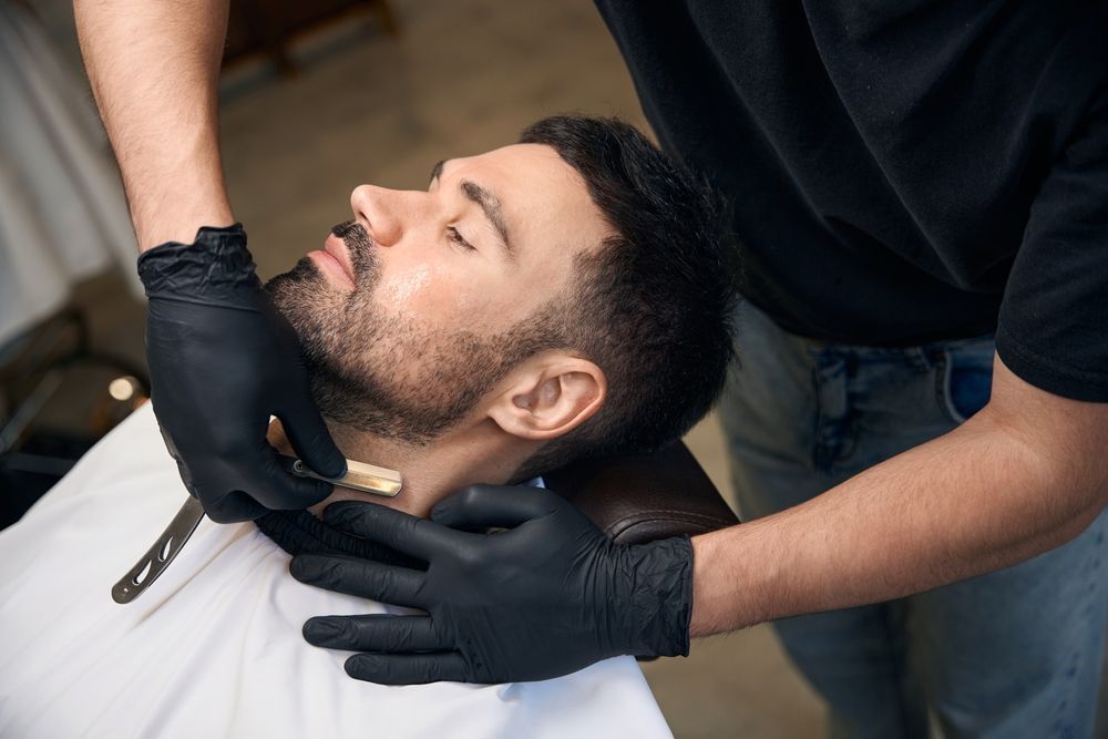 A Barber Applying a Beard Trim to A Reclining Client — Ultimate Barber in Maryborough, QLD